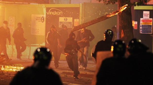 A rioter throws a burning wooden plank at police in Tottenham Aug. 7, 2011. (Lewis Whyld/PA/AP)